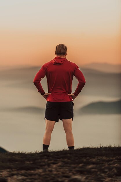 Ein Athlet ruht sich nach einem anstrengenden Lauftraining auf einem Berg aus.