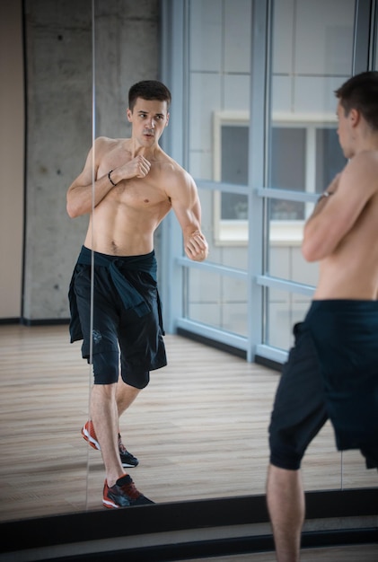 Ein athletischer Mann, der im Studiotraining vor dem Spiegel in Kampfpose steht