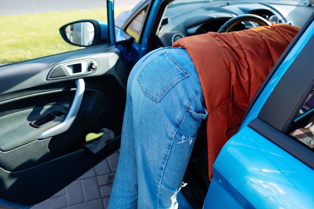 Ein attraktives Mädchen in Jeans lehnte sich auf dem Beifahrersitz ins Auto. Mädchen reinigt im Auto.