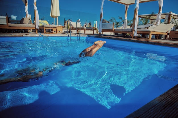 Ein attraktives Paar, ein hübscher muskulöser Mann und eine sexy Frau springen ins Wasser. Urlaub genießen.