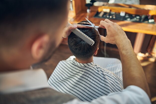 Ein aufmerksamer friseur, der seinem kunden in einem modernen friseursalon einen frischen haarschnitt verpasst