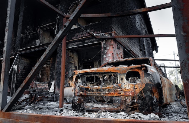 Ein ausgebranntes, zerstörtes Auto in der Nähe eines zivilen Gebäudes Das Ergebnis eines Mörserbeschusses der russischen Invasion in der Ukraine