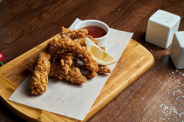 Ein ausgezeichneter Biersnack ist ein Satz Hühnernuggets mit Pergamentsauce auf einem Steintablett. Pub Essen. Nahansicht.