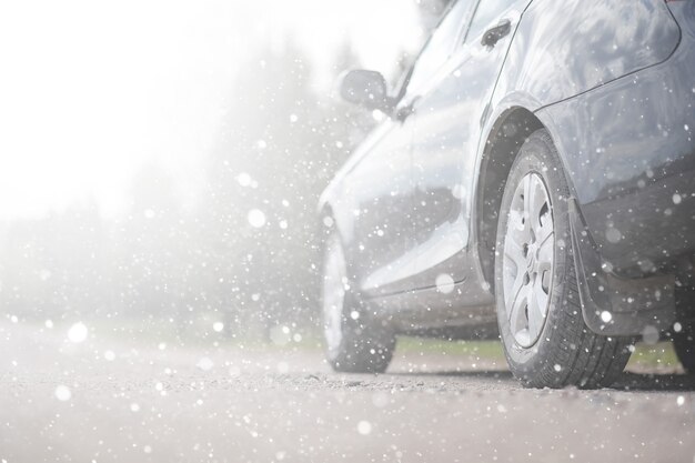 Ein Auto auf der Landstraße im ersten Herbstschnee. Der erste Winterschnee auf der Landstraße, das Auto unter dem Schnee.