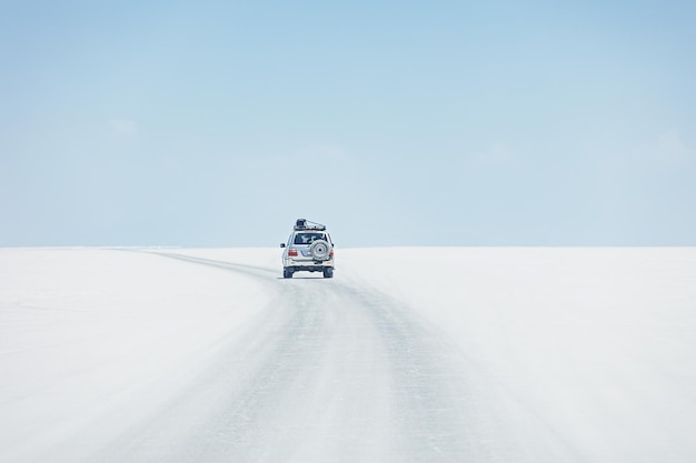 Ein Auto fährt durch den Salzsee Salar de Uyuni in Bolivien