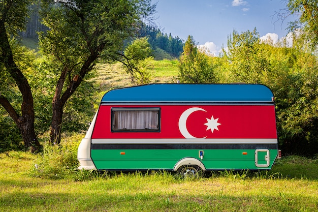 Ein Autoanhänger, ein Wohnmobil, gemalt in der Nationalflagge von Aserbaidschan, steht in einem Bergpark.