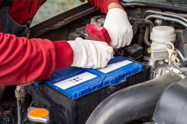 Ein Automechaniker baut eine Batterie in ein Auto ein. Batteriewechsel und Reparatur