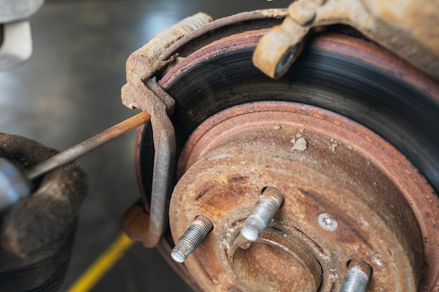 Ein Automechaniker schleift vor dem Belagwechsel Rost an den Bremsscheiben ab, Nahaufnahme replacing