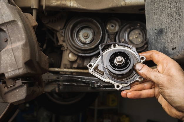 Ein Automechaniker zeigt die ausgebaute alte Motorpumpe