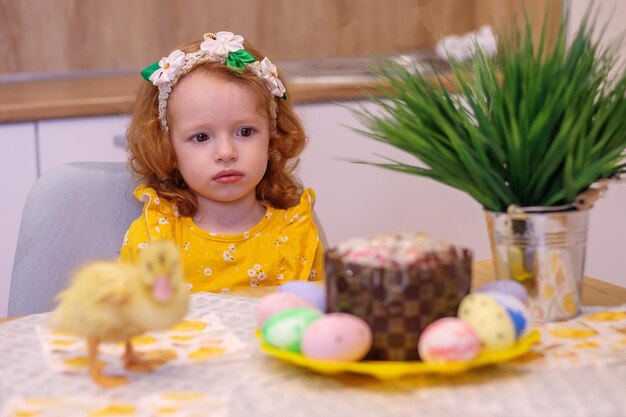 Ein Baby für Ostern mit kleinen gelben Küken neben dem Kuchen und bemalten Eiern Holiday Family Happiness