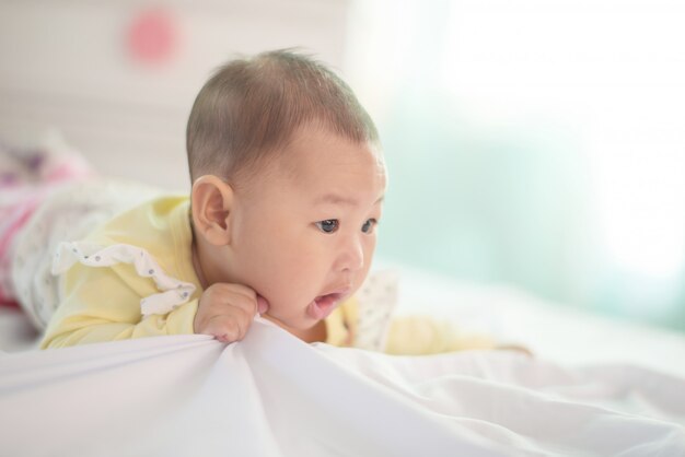 Ein Baby in der weißen Bettwäsche zu Hause.