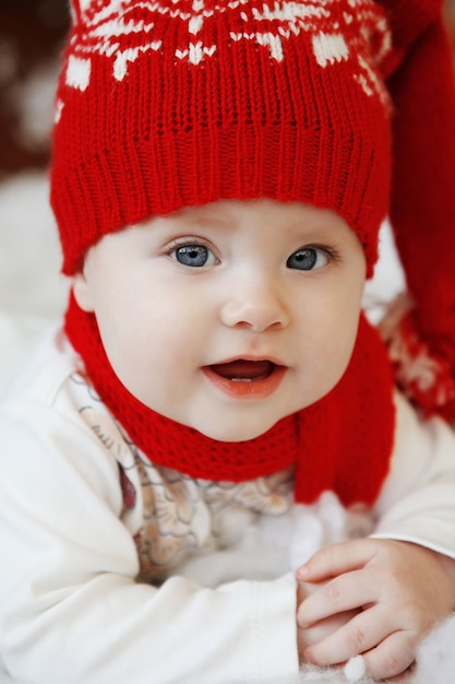 Ein Baby in einer roten Mütze mit Kugeln im Innenraum des neuen Jahres.