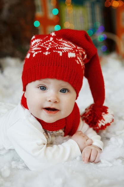 Ein Baby in einer roten Mütze mit Kugeln im Innenraum des neuen Jahres.