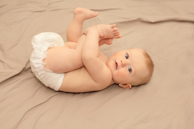 Ein Baby liegt mit erhobenen Füßen und Füßen auf einem Bett.