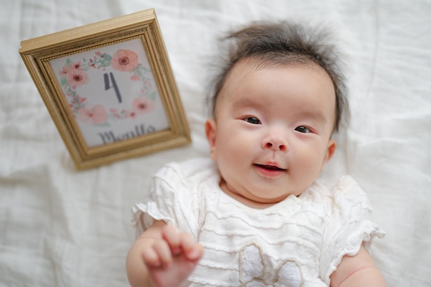 Ein Baby liegt neben einem gerahmten Bild mit der Nummer 4 darauf.