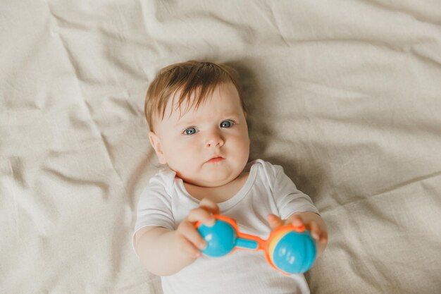 Ein Baby mit einem Zähner und einem Rassel auf einem Baumwollbett Zähnen Kinderartikel Kopierraum