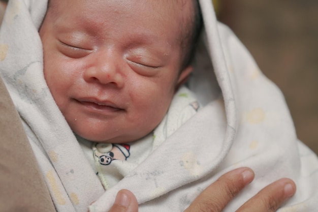 Ein Baby mit geschlossenem Auge und seiner Hand