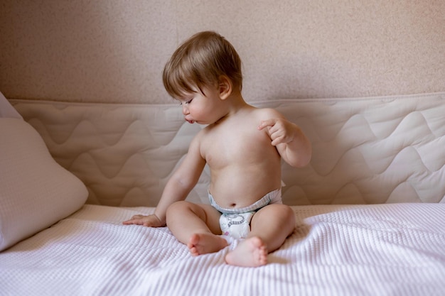 Ein Baby sitzt auf einem Bett mit einem Kissen darauf