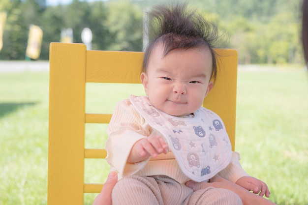 Ein Baby sitzt auf einer gelben Bank in einem Park.