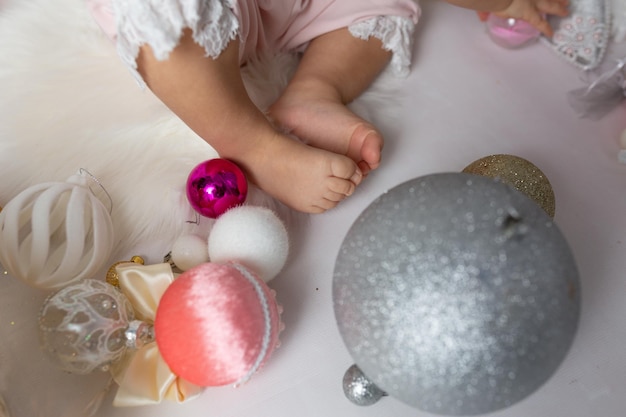 Ein Baby sitzt auf einer weißen Fläche mit einem Weihnachtsbaum im Hintergrund.