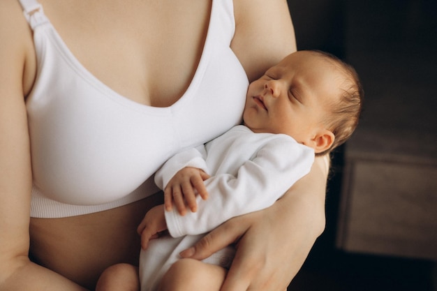 ein Baby wird von einer Frau mit den Armen um ihr herum gehalten