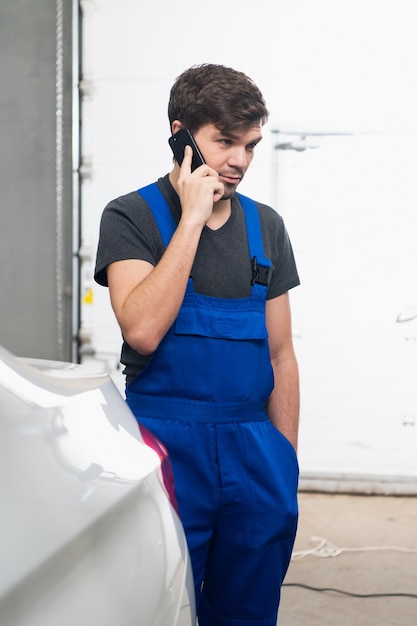 Ein bärtiger Handwerker in Uniform spricht auf einem Handy