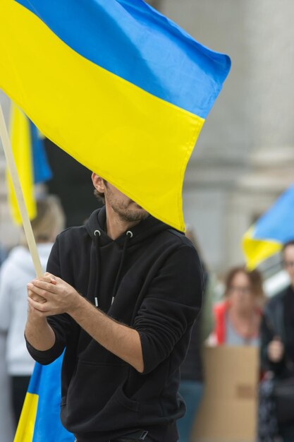 Ein bärtiger Mann hält während des Protests die ukrainische Flagge