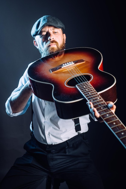 Ein bärtiger Mann mit Hut und Gitarre im Studio