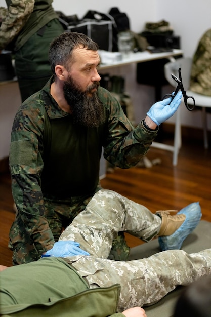Ein bärtiger Militärsanitäter demonstriert taktische medizinische Scheren