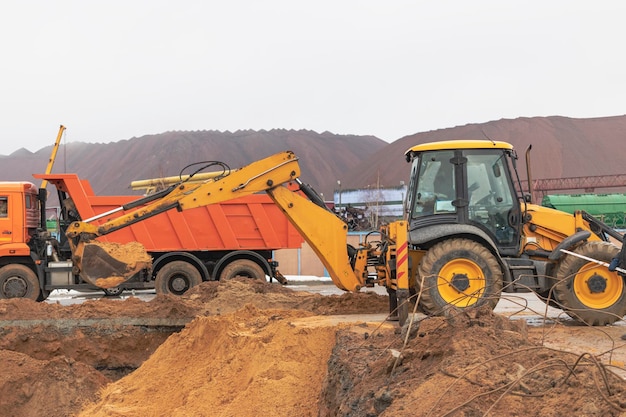 Ein Bagger lädt Erde oder Sand in einen Muldenkipper Grubenentwicklung Erdarbeiten mit Hilfe von schwerem Baugerät