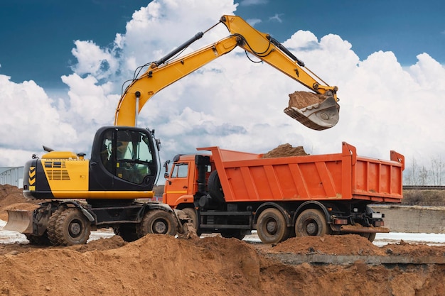 Ein Bagger lädt Erde oder Sand in einen Muldenkipper Grubenentwicklung Erdarbeiten mit Hilfe von schwerem Baugerät