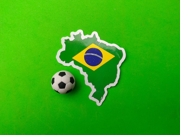 Ein Ball und ein Brasilien-Flaggenaufkleber sind auf grünem Hintergrund