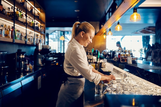 Ein Barkeeper arbeitet mit sauberen Gläsern hinter einer Theke in einer Bar