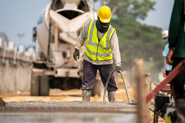 Ein Bauarbeiter, der einen nassen Beton an der Straßenbaustelle gießt