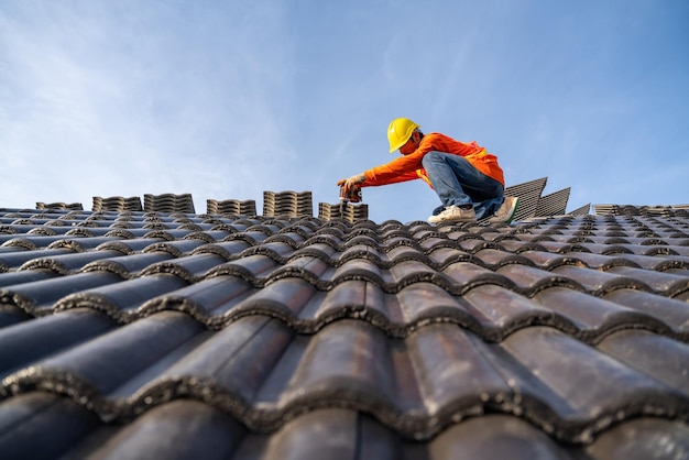 Ein Bauarbeiter installiert ein neues Dach Elektrische Bohrmaschine, die auf neuen Dächern mit Betondachziegel-Dachwerkzeugen verwendet wird