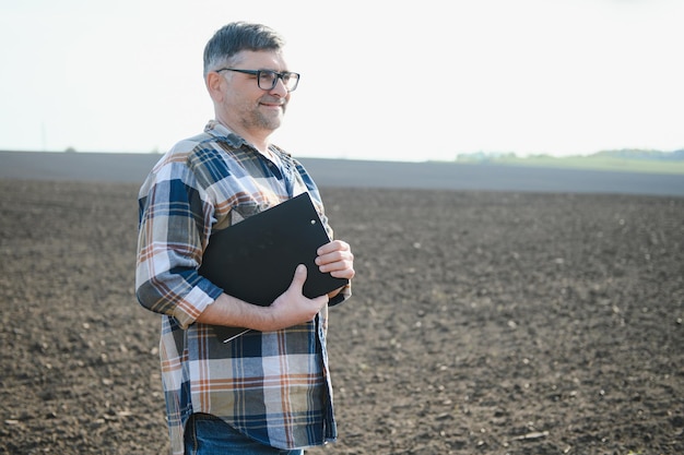 Ein Bauer arbeitet auf einem im Frühjahr gesäten Feld. Ein Agronom geht um die Erde und beurteilt ein gepflügtes Feld im Herbst. Landwirtschaft Intelligente Landwirtschaftstechnologien