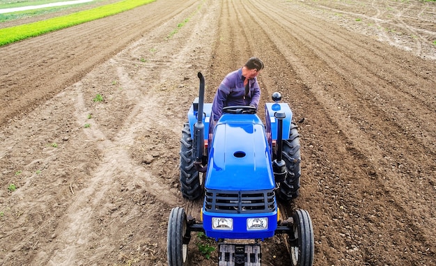 Ein Bauer auf einem Traktor bewirtschaftet ein landwirtschaftliches Feld. Bodenmahlen zerbröckeln und mischen