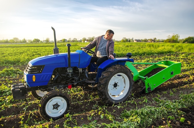 Ein Bauer auf einem Traktor gräbt Kartoffeln mit einem Bagger Der Einsatz moderner Technik auf dem Bauernhof