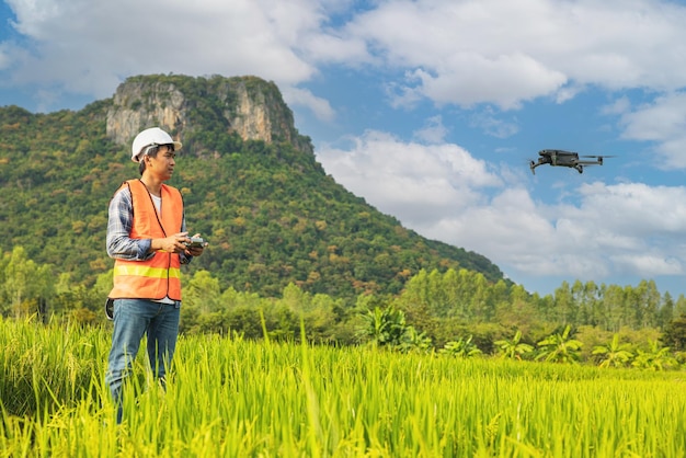 Ein Bauer in einer Kappe steht in einem üppigen Weizenfeld und leitet eine Drohne, die über den Rand fliegt. Mann, der die Ausrüstung steuert Landwirtschaftstechnologien