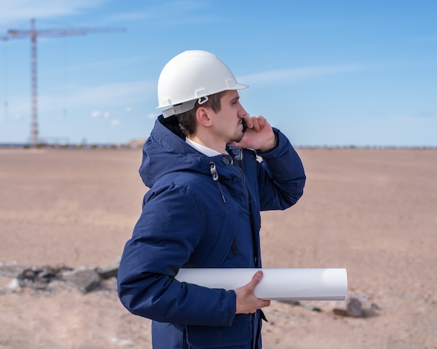 Ein Bauingenieur in einem weißen Helm telefoniert gerade im Bau.