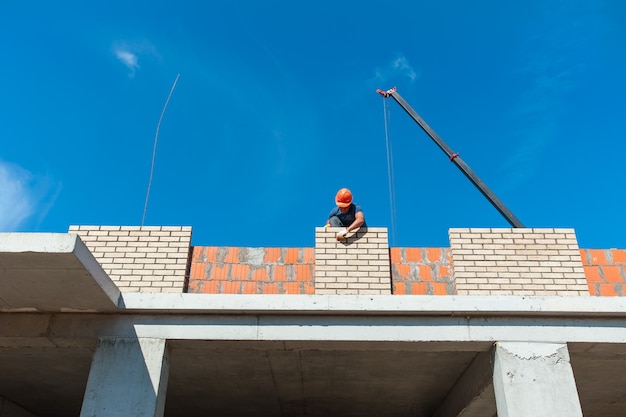 Ein Baumeister legt eine Backsteinmauer eines neuen Hauses im Bau an