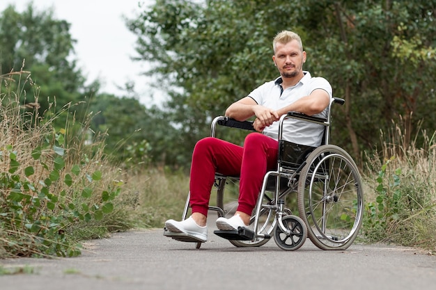 Ein behinderter Mann sitzt im Rollstuhl auf der Straße. Das Konzept eines Rollstuhls, einer behinderten Person, eines vollen Lebens, einer gelähmten, einer behinderten Person, einer Gesundheitsversorgung.