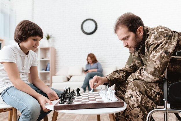 Ein behinderter Mann spielt mit seinem Sohn im Schach.