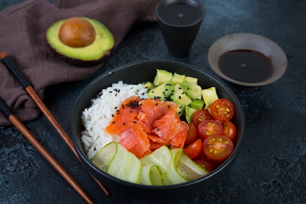 Ein beliebtes hawaiianisches Gericht, stecken Sie in einen Teller mit rotem Fisch, Reis und Gemüse. Sackplatte auf einem schwarzen Betonhintergrund