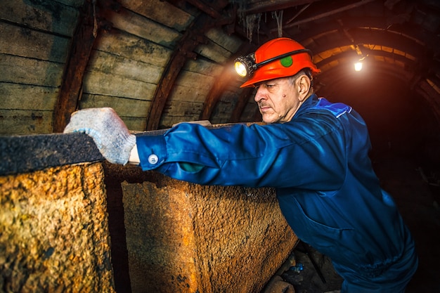 Ein bergmann in einer kohlengrube steht in der nähe eines wagens. kopieren sie platz.