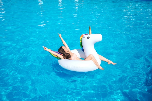 Ein Bild des Mädchens, das allein im Pool schwimmt. Sie liegt auf einer Luftmatratze und posiert. Mädchen ruht sich aus. Sie hat Spaß.