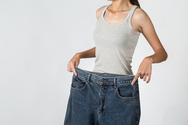 Ein Bild einer jungen Frau in den losen Jeans, die Effekte der Diät ihren Körper zeigen