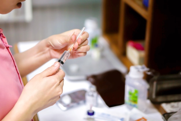 Ein Bild von Krankenschwesterhänden, die eine Plastikspritze zur Vorbereitung eines Injektionsimpfstoffs für den Patienten halten.