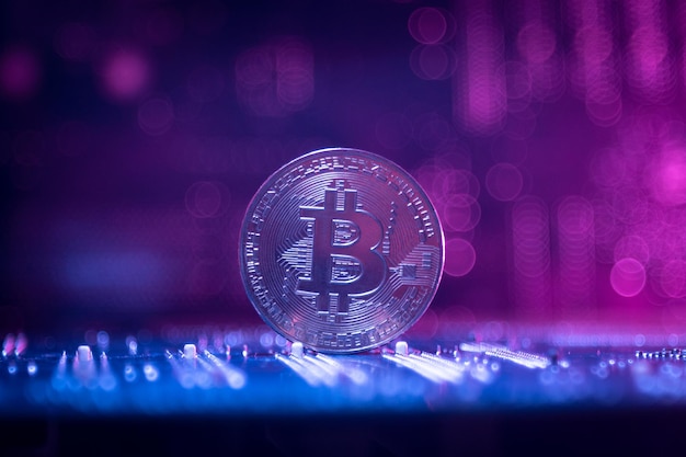 Ein Bitcoin auf dem Hintergrund von Microboards. Neon-Magenta. Nahansicht.