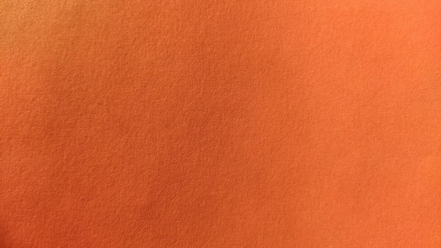 Ein Blatt dickes Papier in helloranger Farbe Nahaufnahme Hintergrund intensiver Schatten Natürliche seitliche Beleuchtung Feine Karton- oder Papierstruktur Leichter Farbverlauf im Beleuchtungsgrad